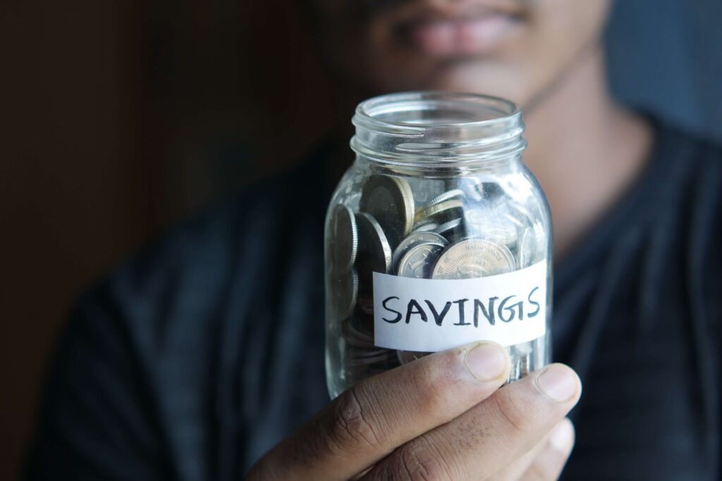 A person holding a saving jar filled with coins